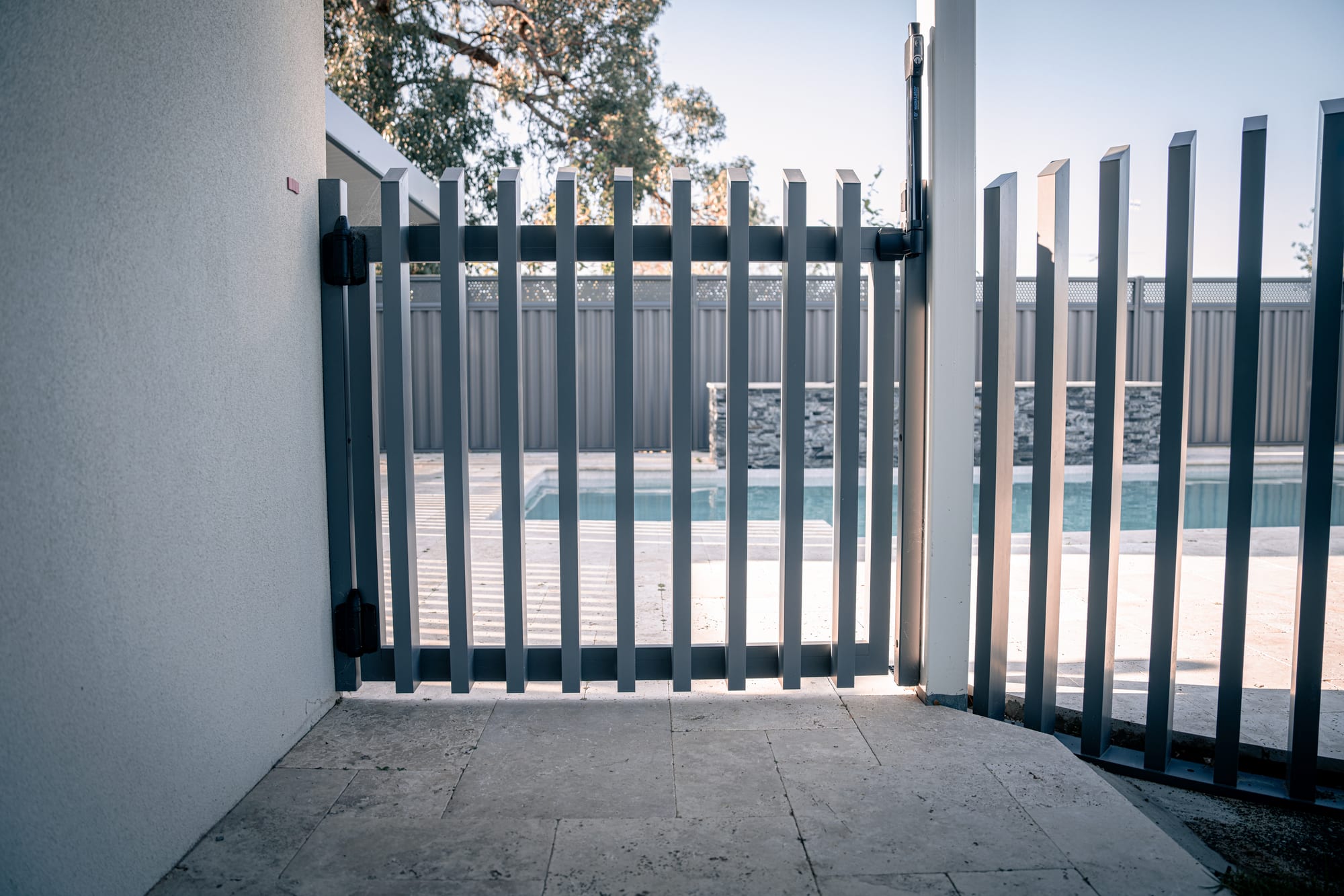 A charcoal aluminium pool gate with a magnetic pool safety latch and black hinges