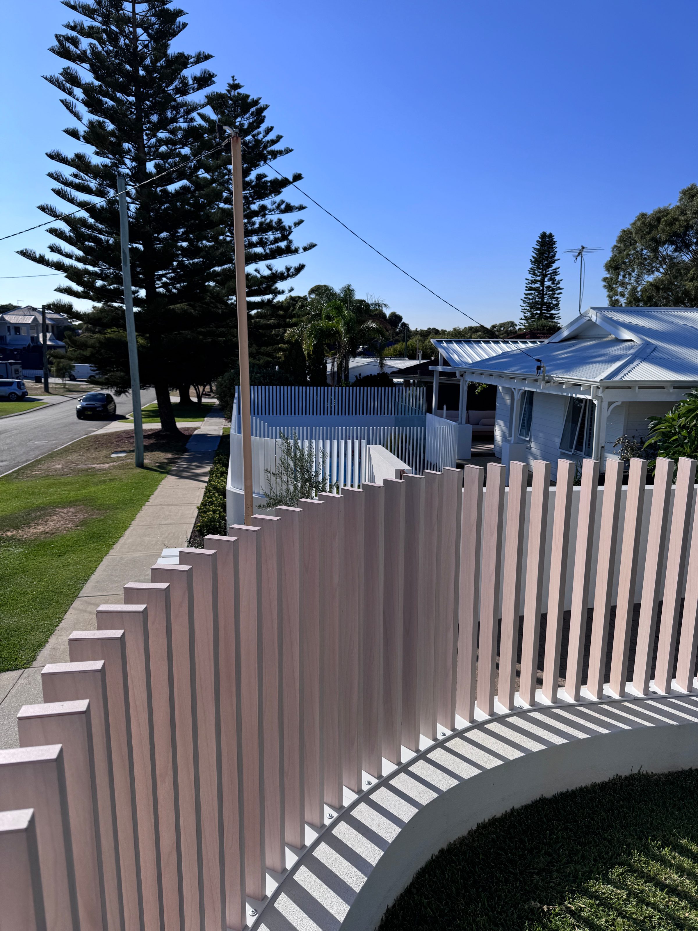 A woodlook aluminium fence curving along a coastal path
