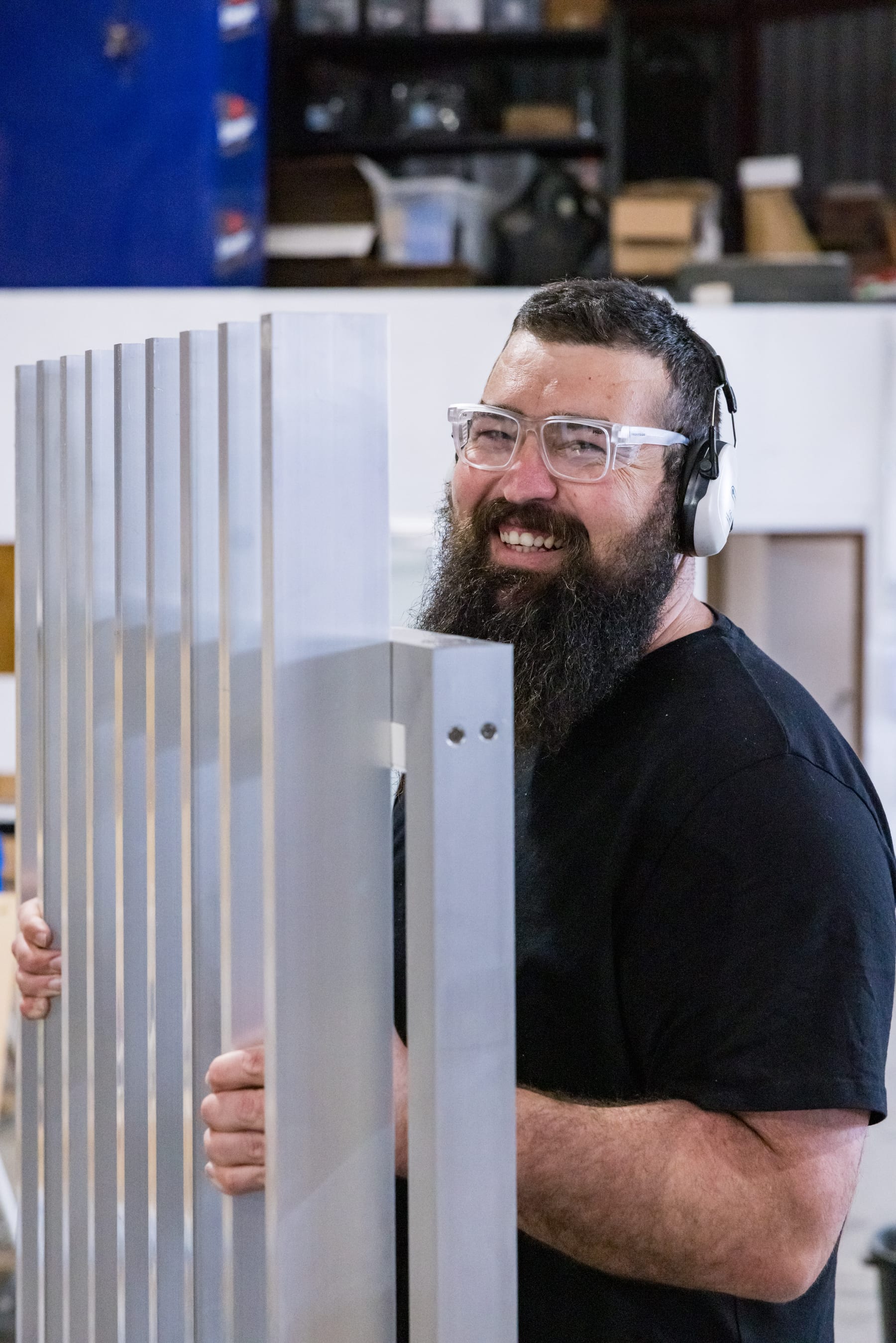 An AFS fabricator carrying a raw aluminium panel through the factory