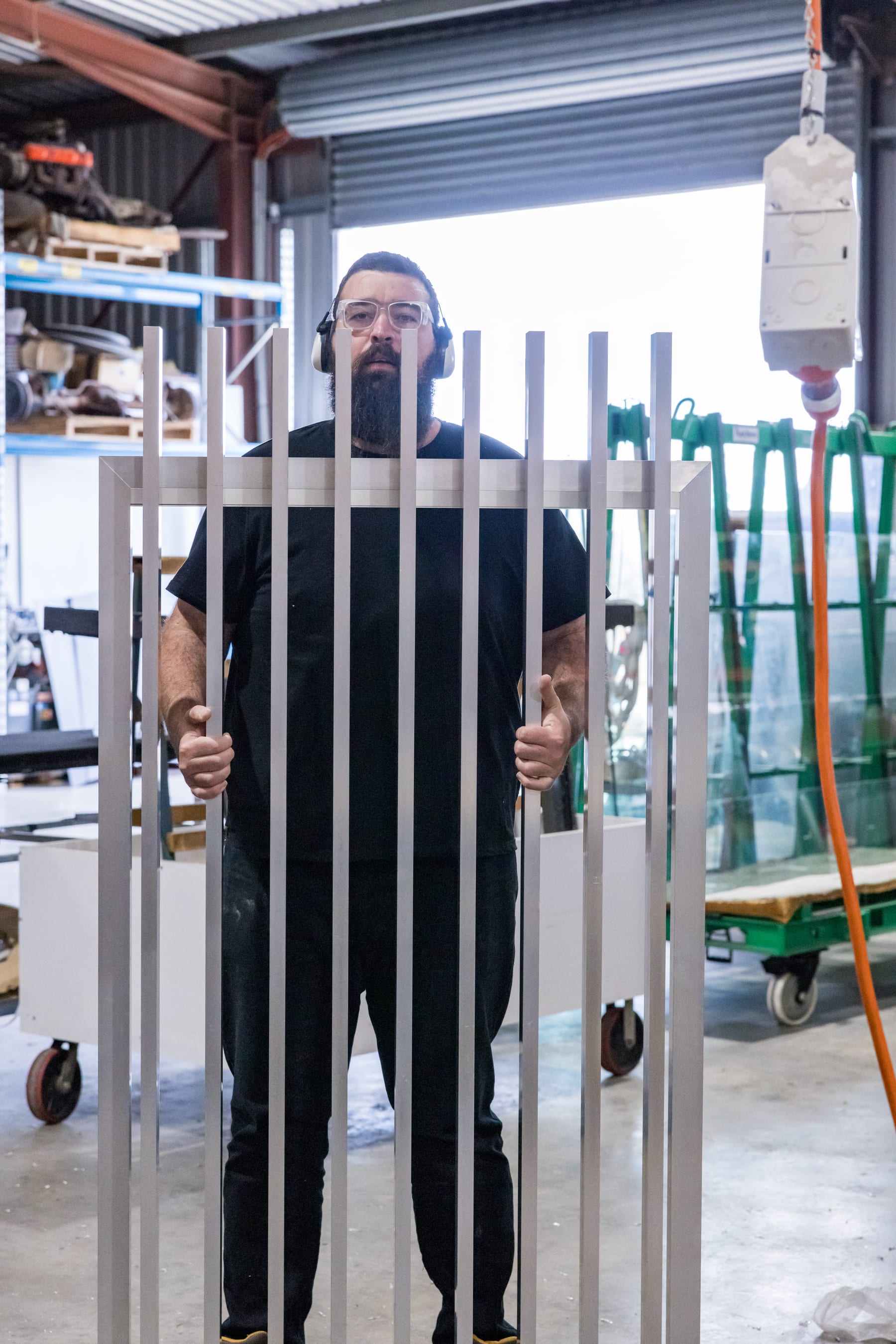 A worker behind a raw aluminium panel frame on the AFS factory floor