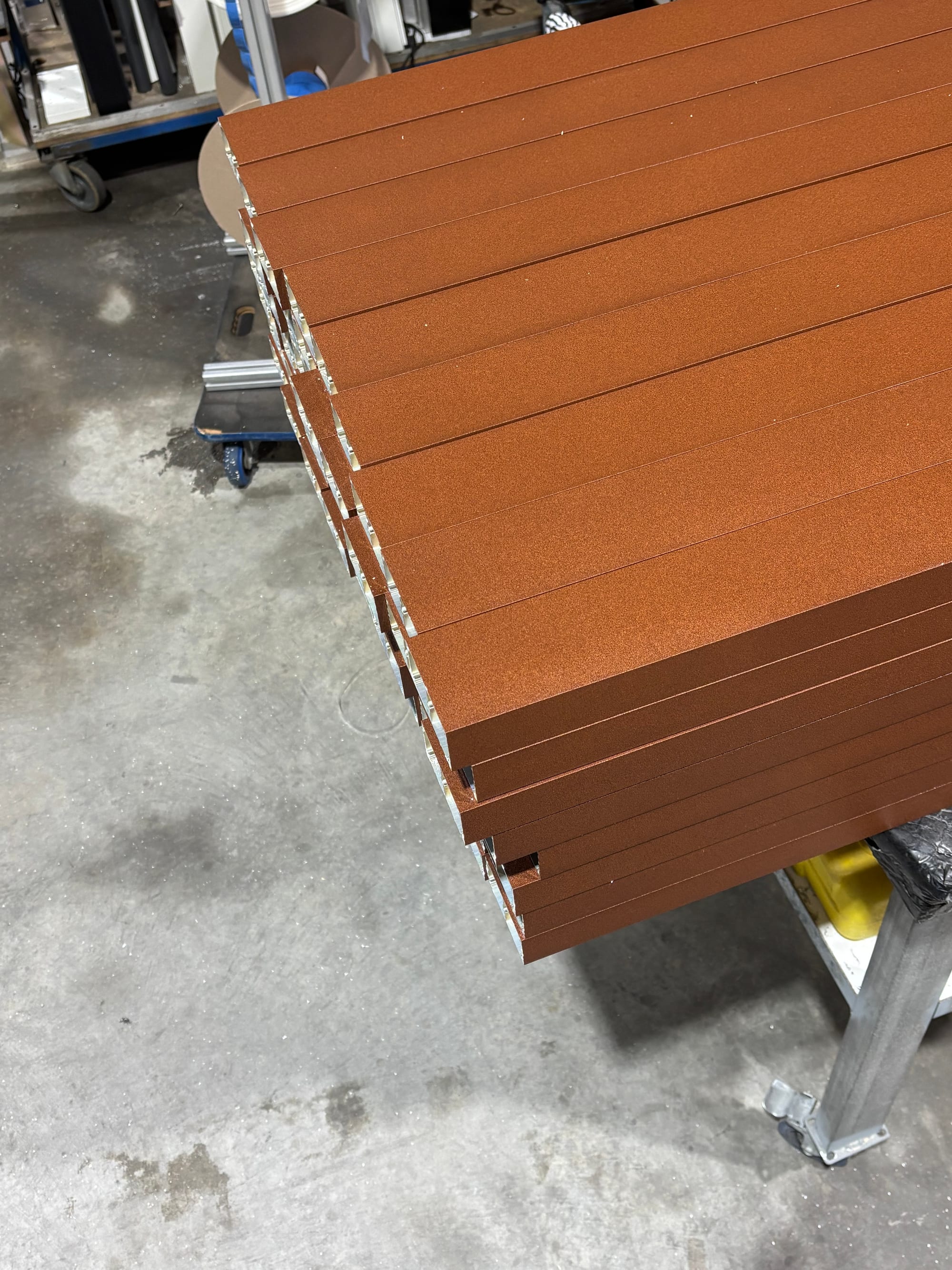 Freshly powder coated aluminium sections stacked on a workshop trolley